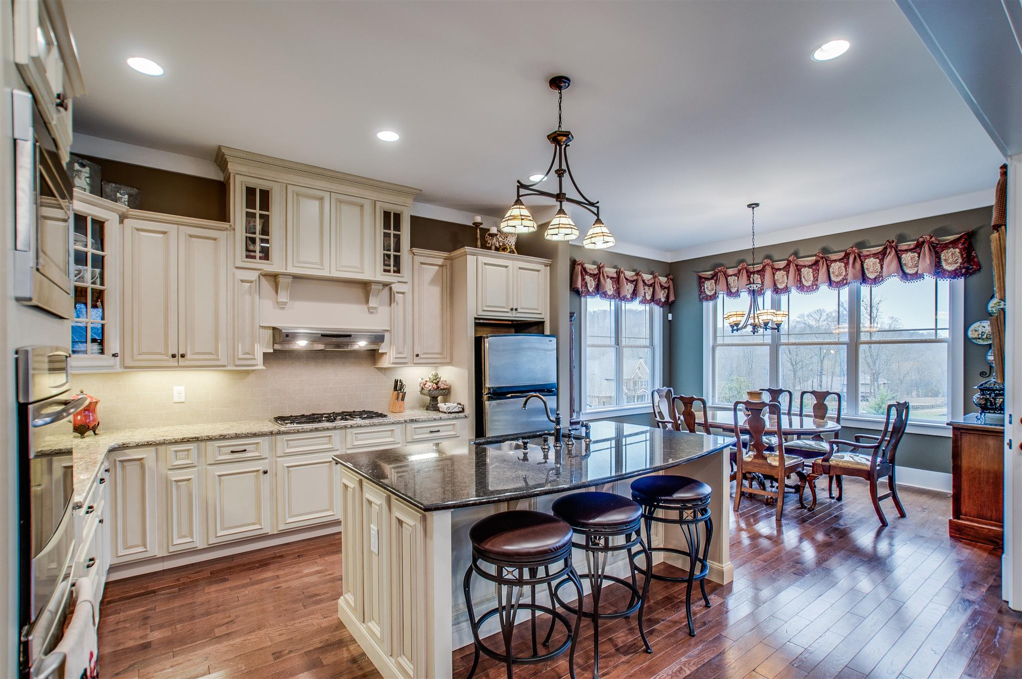 2533 Belle Brook Drive Franklin, TN 37067 - Photo 13 of 30 a kitchen with stainless steel appliances granite countertop a stove top oven a sink dishwasher a dining table and chairs with wooden floor