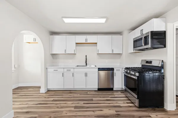 a view of a kitchen with wooden floor electronic appliances and windows