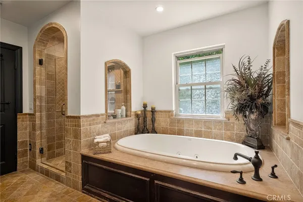 a bathroom with a granite countertop tub a sink and a large mirror