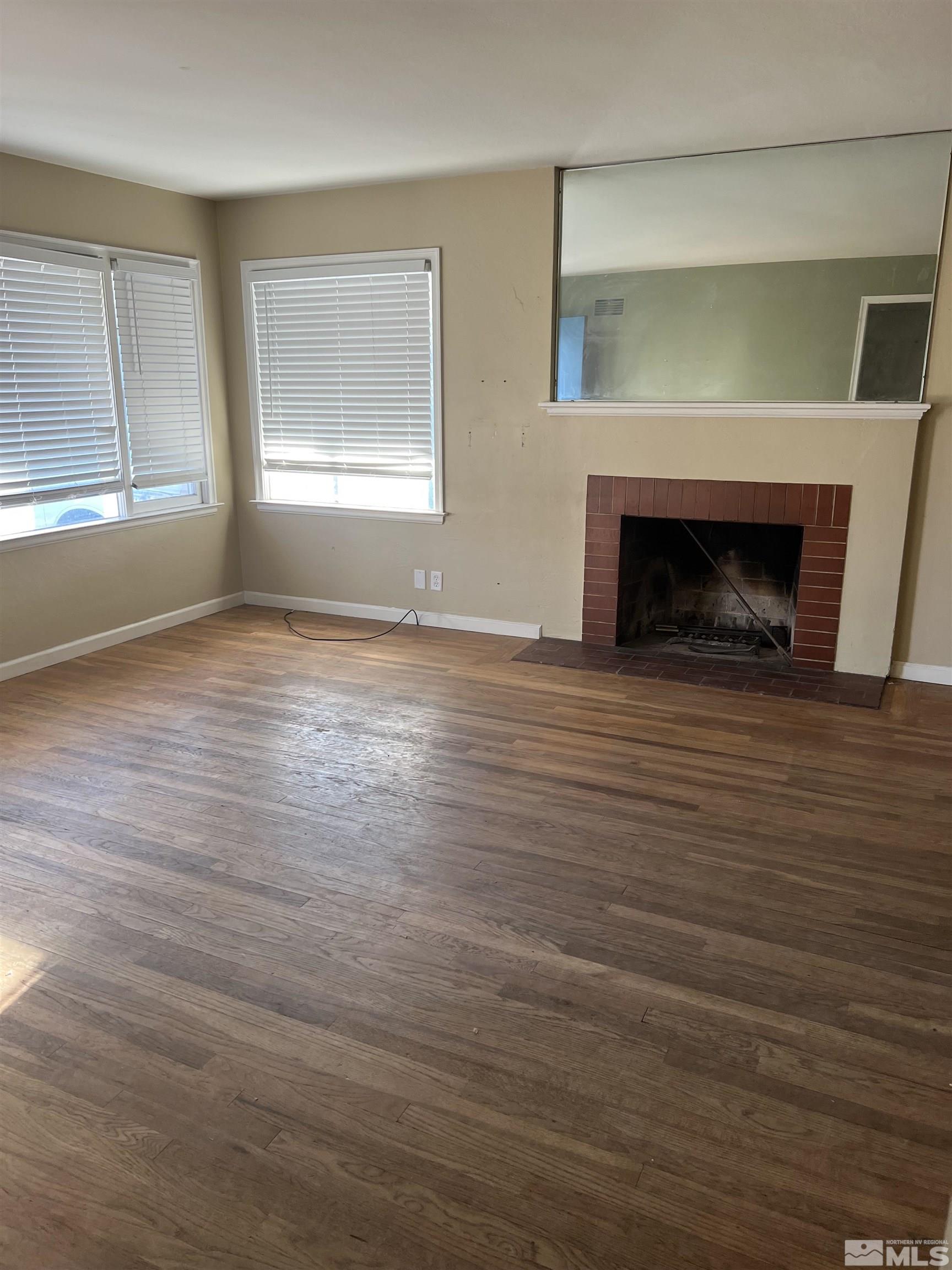 1575 Allen Street Reno, NV 89509 - Photo 2 of 8 an empty room with wooden floor fireplace and windows
