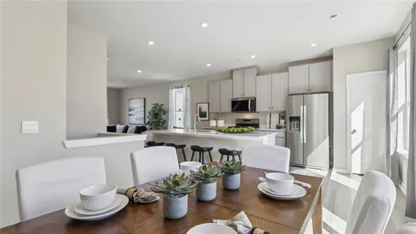 a kitchen with stainless steel appliances granite countertop a stove a refrigerator a sink dishwasher a dining table and chairs with wooden floor