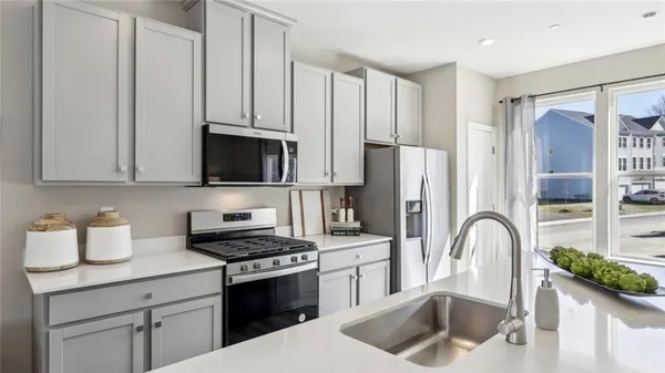 a kitchen with stainless steel appliances a stove a refrigerator a sink a stove and white cabinets