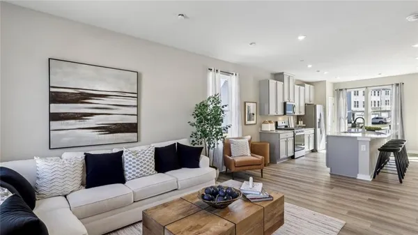 a living room with furniture potted plant and kitchen view