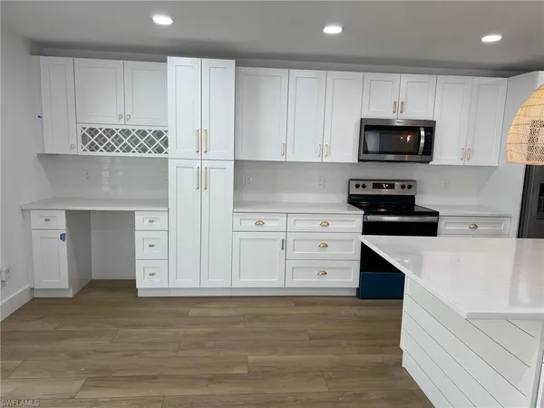 a kitchen with granite countertop a refrigerator oven a stove with white cabinets