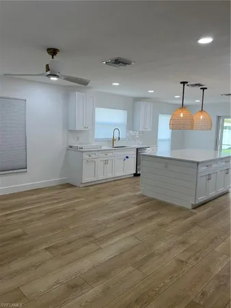 a large white kitchen with kitchen island a sink stainless steel appliances and cabinets