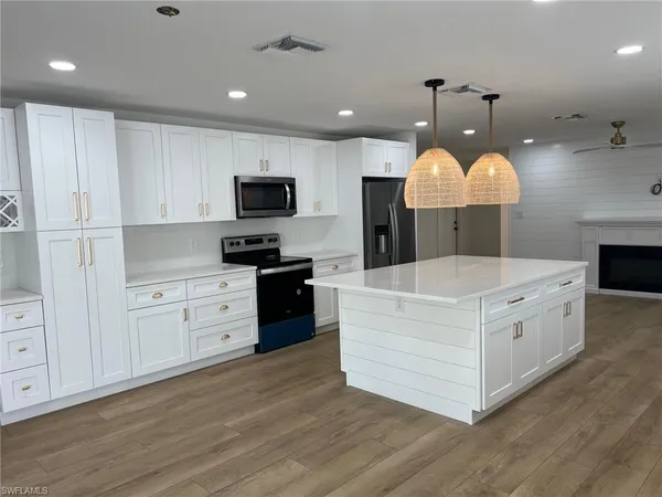 a large white kitchen with a stove top oven and wooden floor