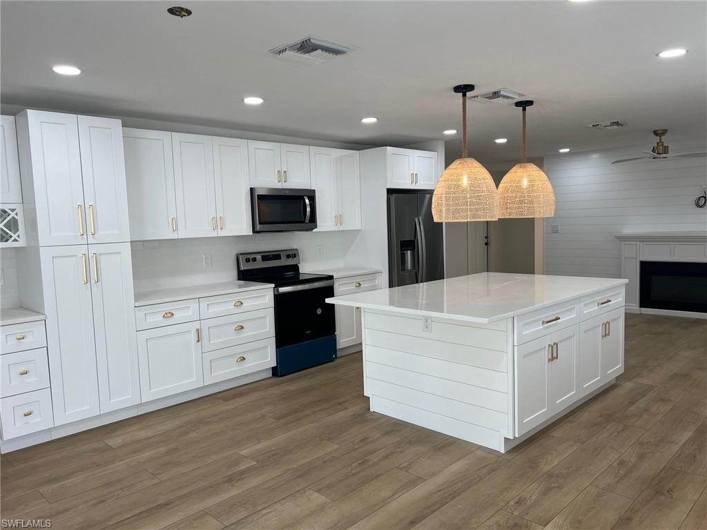 673 107th Avenue North Naples, FL 34108 - Photo 8 of 15 a large white kitchen with a stove top oven and wooden floor