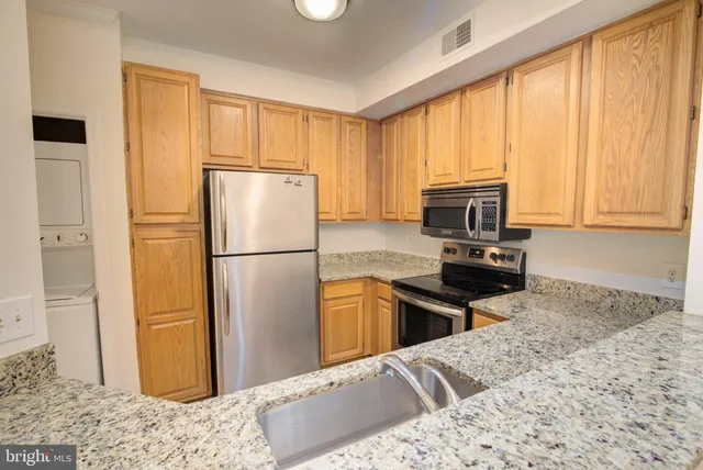a kitchen with a refrigerator stainless steel appliances granite countertop cabinets and a window