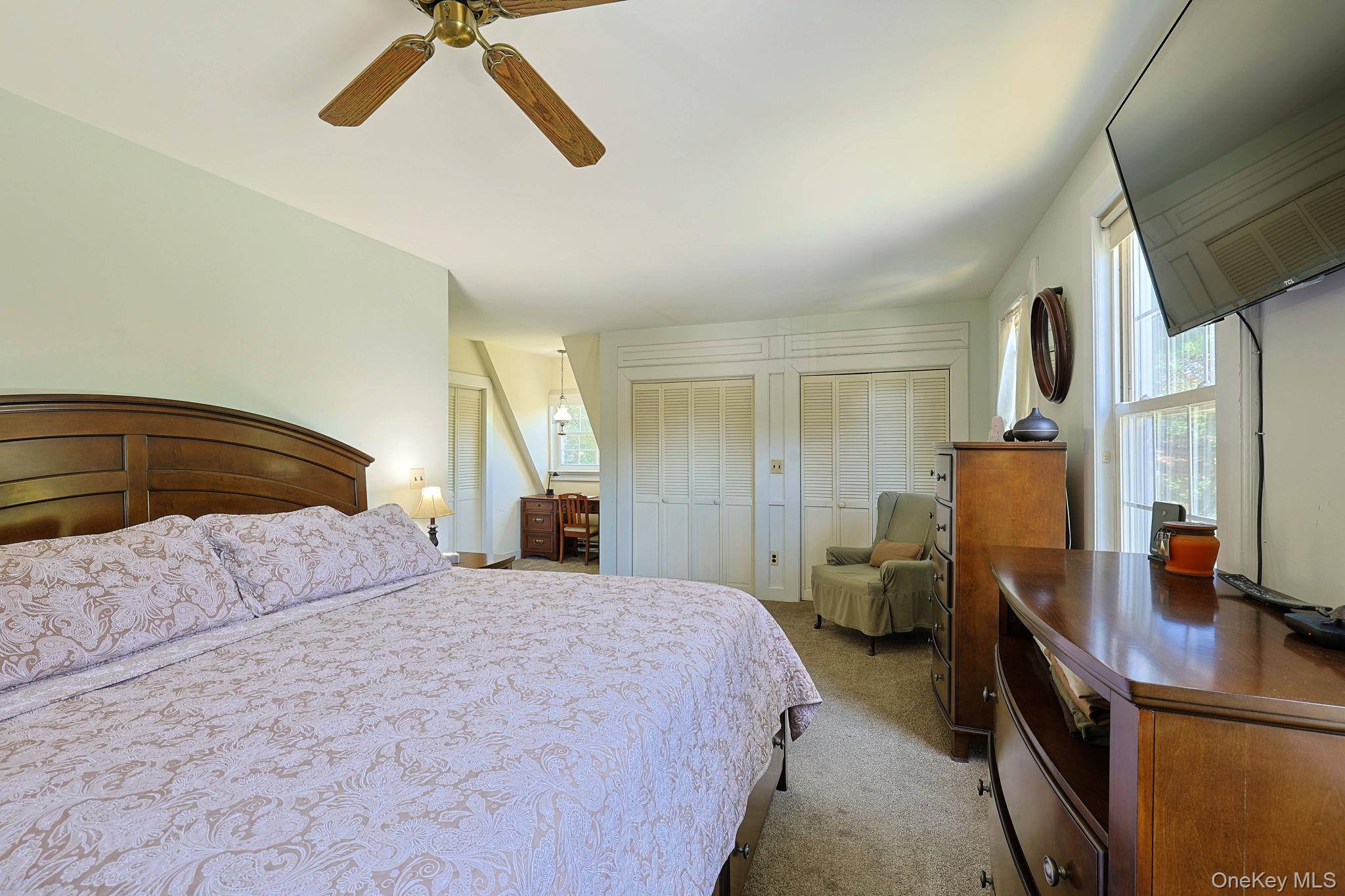 9 Library Road Tuxedo Park, NY 10987 - Photo 17 of 37 Spacious Primary bedroom with a wood-finish ceiling fan, neutral carpet, and multiple windows providing natural light