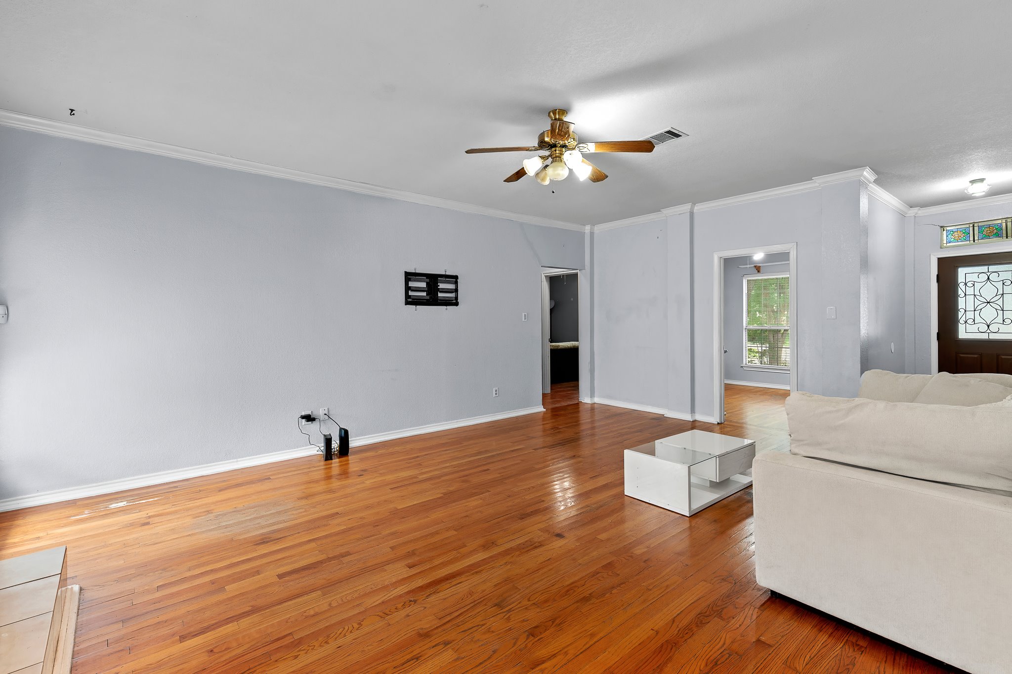 11737 Rydalwater Lane Austin, TX 78754 - Photo 11 of 40 Spacious living area featuring wood-finish flooring, light gray walls, white crown molding, and a ceiling fan with integrated lighting