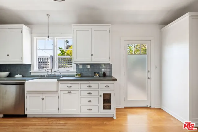 a kitchen with stainless steel appliances white cabinets and a wooden floors