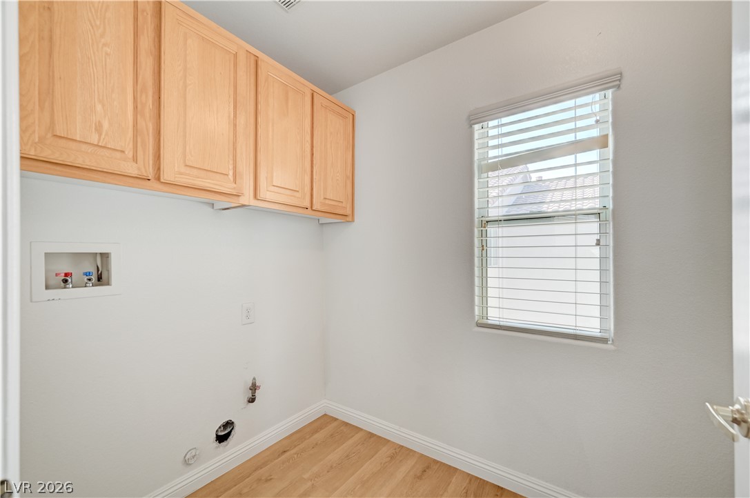 8918 Houston Ridge Avenue Las Vegas, NV 89178 - Photo 33 of 35 An organized laundry area includes rich wood cabinetry and light wood-look flooring.