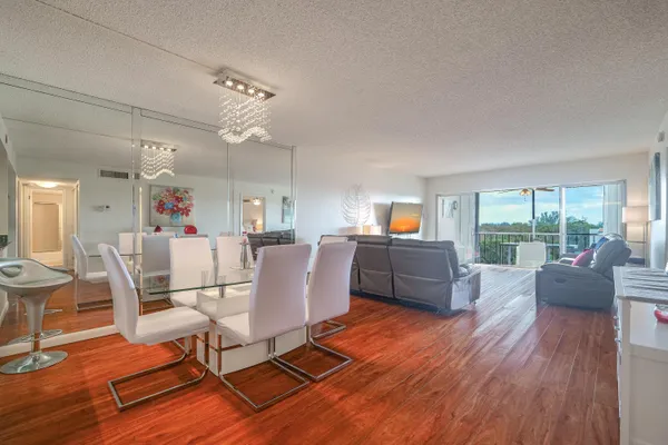 a living room with furniture and a dining table with wooden floor