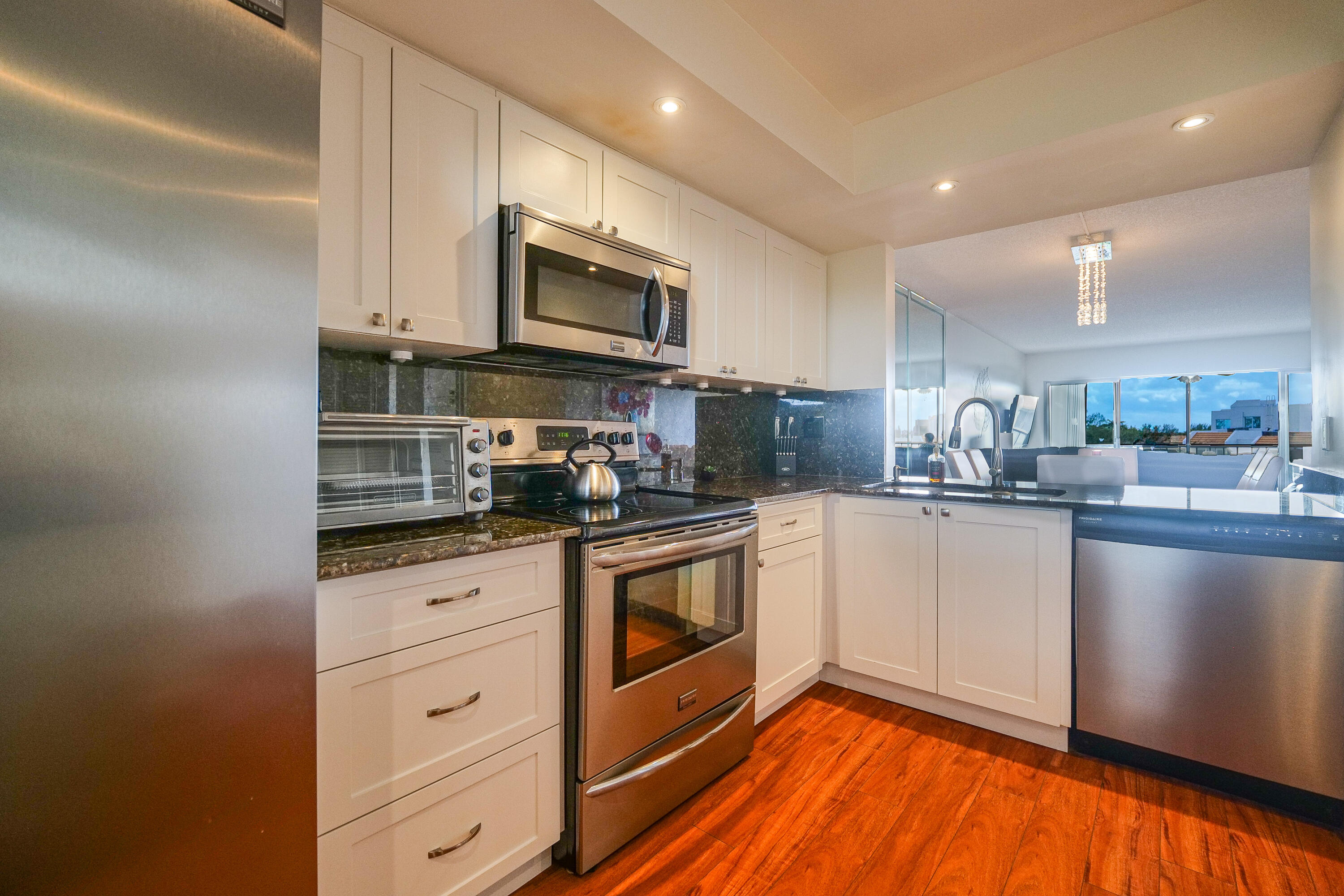 3930 Inverrary Boulevard, Unit 703D Lauderhill, FL 33319 - Photo 13 of 62 a kitchen with stainless steel appliances granite countertop white cabinets a sink a stove a microwave and a refrigerator