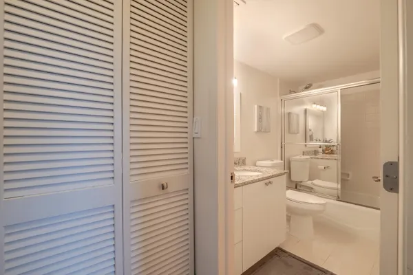 a bathroom with a granite countertop sink a toilet a mirror and shower
