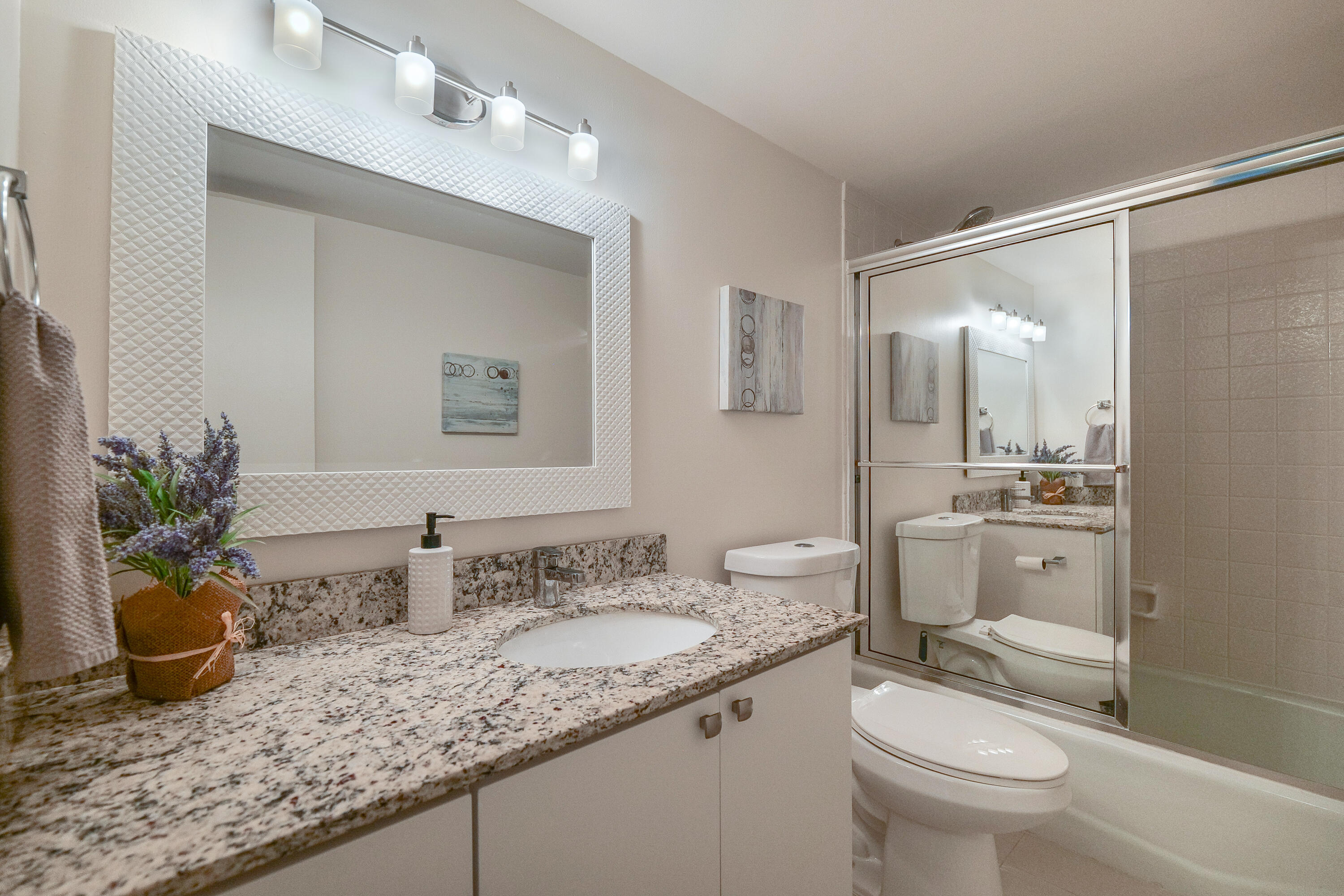 3930 Inverrary Boulevard, Unit 703D Lauderhill, FL 33319 - Photo 23 of 62 a bathroom with a granite countertop sink a toilet a mirror and shower