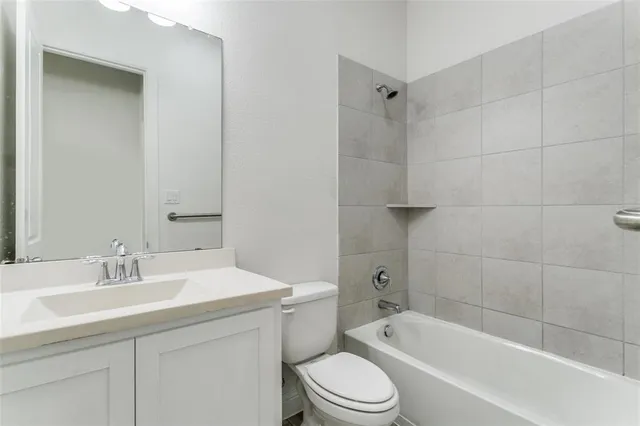 a bathroom with a bathtub shower sink vanity mirror and toilet