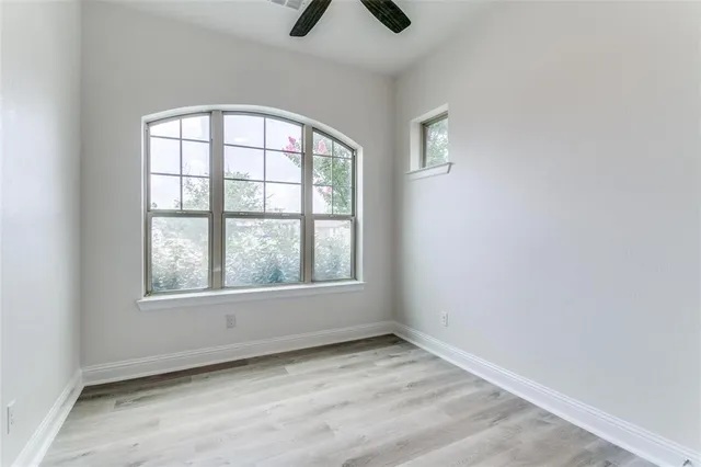 an empty room with windows and fan
