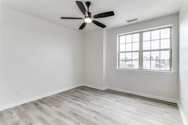 an empty room with a window and a fan