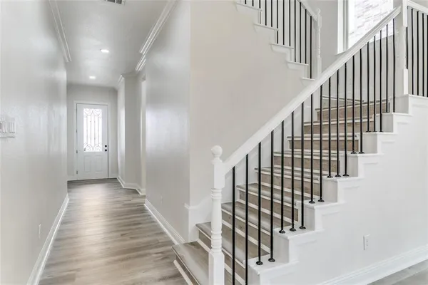 a view of staircase with lots of frames on wall and wooden floor
