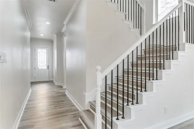 a view of staircase with lots of frames on wall and wooden floor