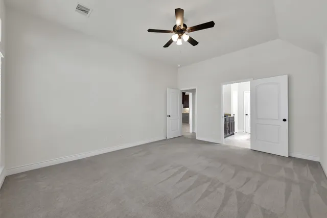 an empty room with ceiling fan and windows