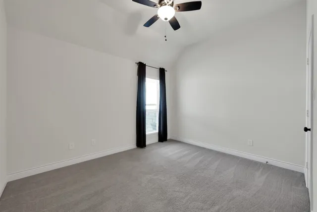 an empty room with a chandelier fan and windows