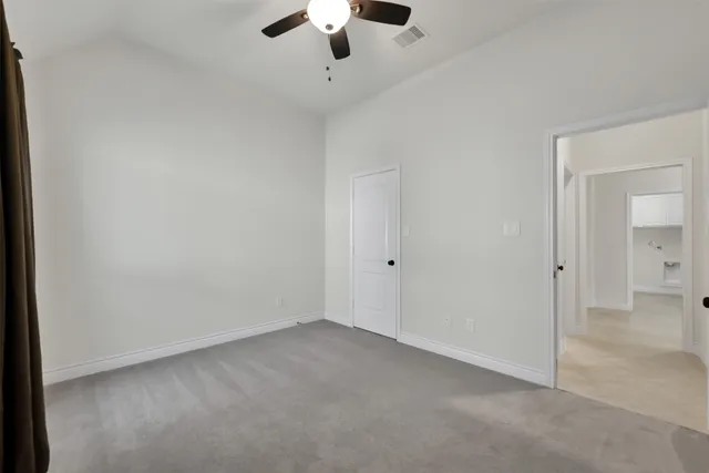 an empty room with a ceiling fan and carpet