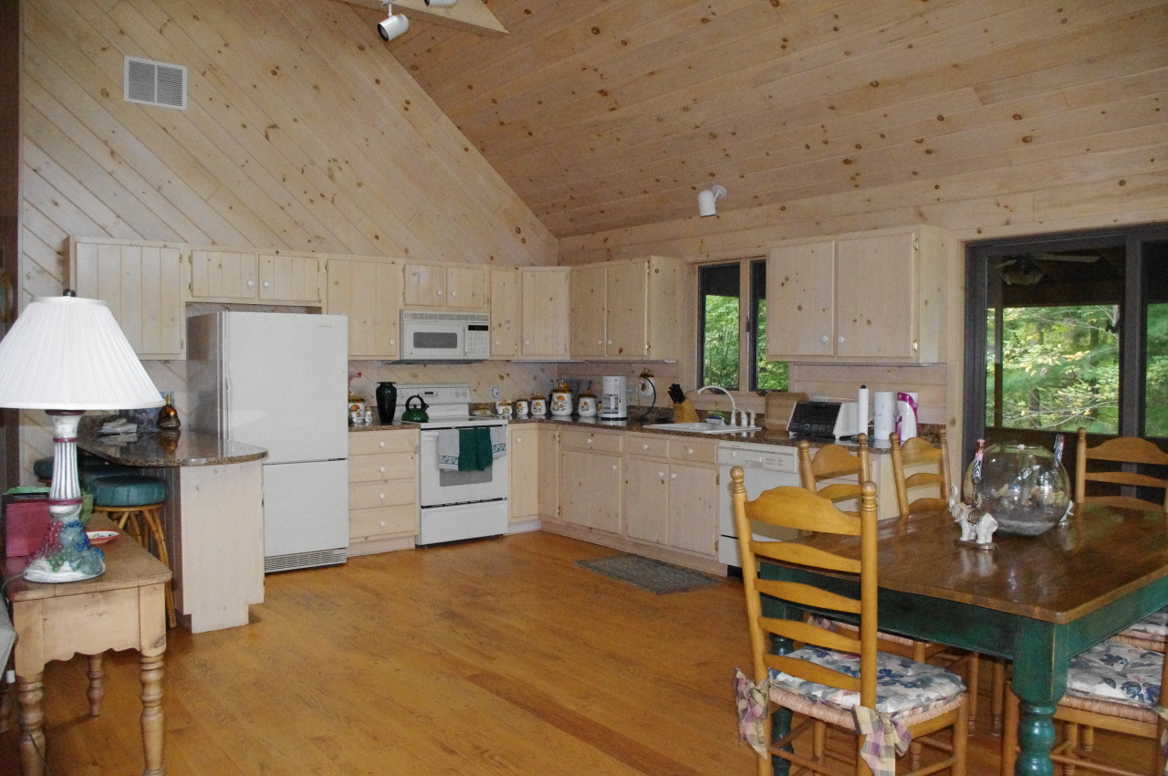 106 Stevens Lake Road Monterey, MA 01245 - Photo 7 of 16 a kitchen with stainless steel appliances granite countertop a stove a refrigerator a kitchen island a table and chairs