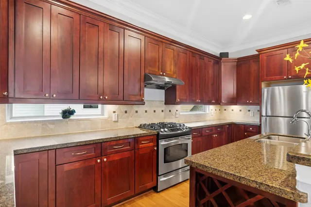 a kitchen with stainless steel appliances granite countertop wooden cabinets a sink and a stove