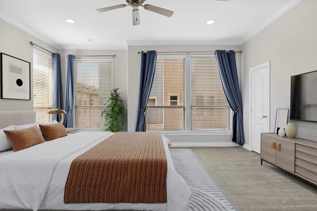 a spacious bedroom with a large bed and a flat tv screen