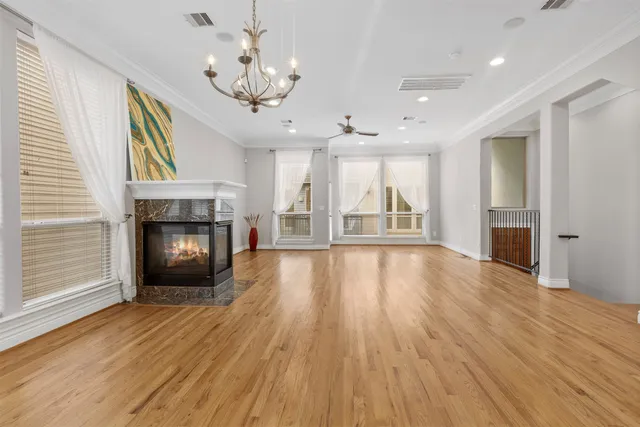 a view of an empty room with wooden floor fireplace and a window