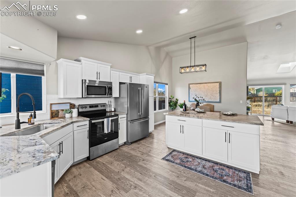 8168 Oliver Road Peyton, CO 80831 - Photo 9 of 42 a kitchen with stainless steel appliances a sink a stove a refrigerator cabinets and a center island