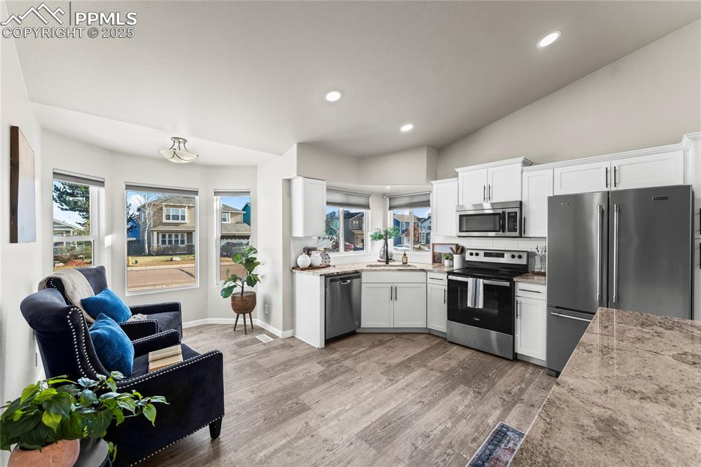 8168 Oliver Road Peyton, CO 80831 - Photo 10 of 42 a kitchen with stainless steel appliances kitchen island granite countertop a refrigerator a stove top oven a sink dishwasher and white cabinets with wooden floor