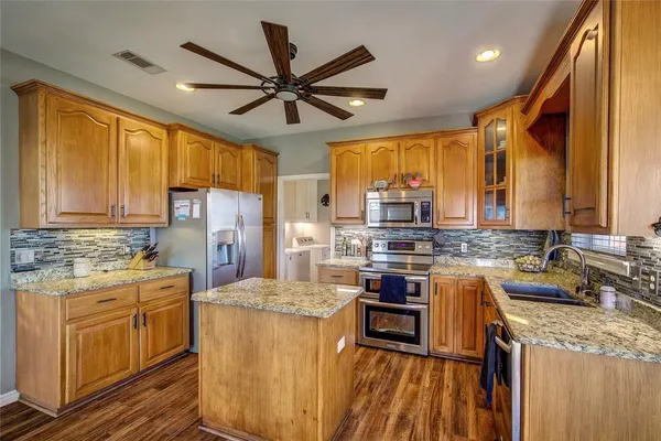 a kitchen with stainless steel appliances kitchen island granite countertop a sink stove and refrigerator