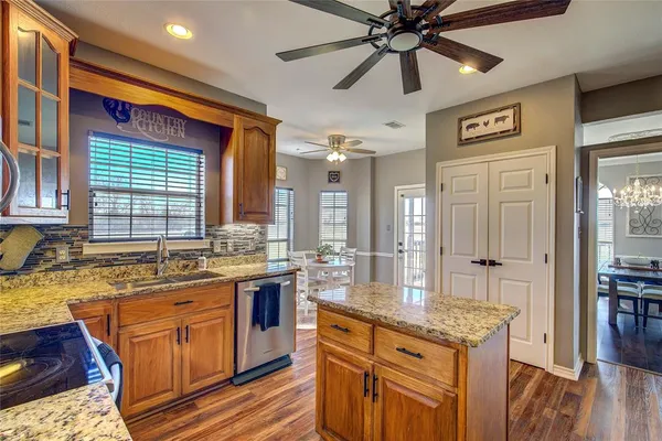 a kitchen with stainless steel appliances granite countertop a sink and wooden cabinets