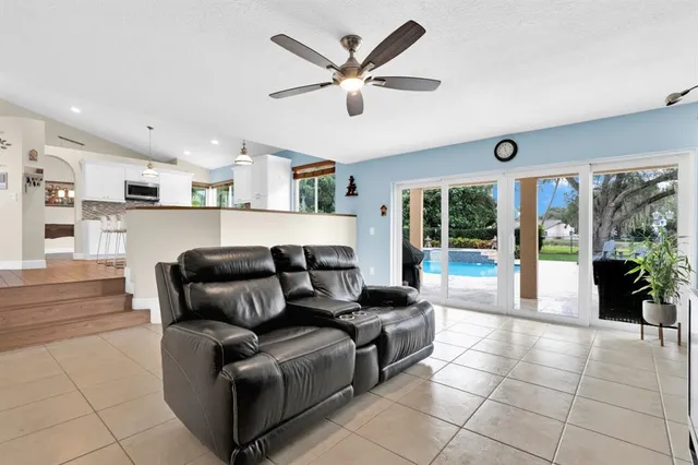 a living room with furniture and a large window with kitchen view
