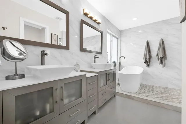 a bathroom with a double vanity sink mirror and bathtub