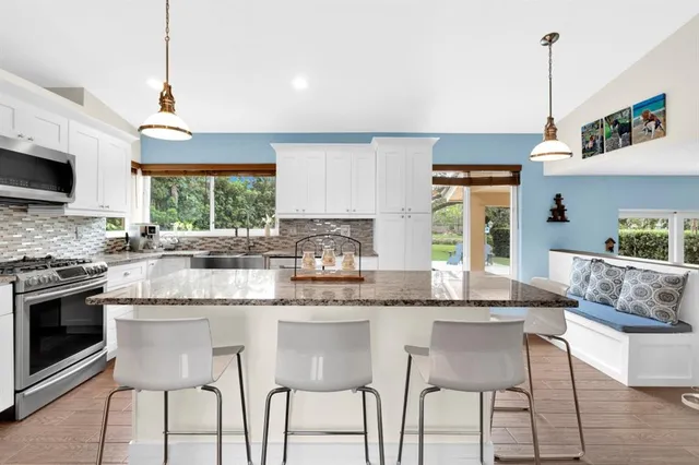 a kitchen with granite countertop white cabinets and stainless steel appliances