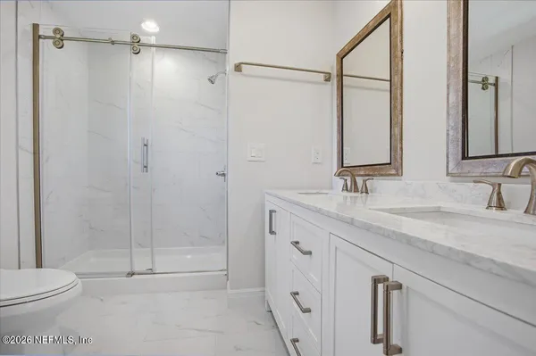 a bathroom with a granite countertop sink a toilet and shower