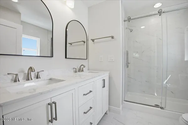 a bathroom with a double vanity sink mirror and shower