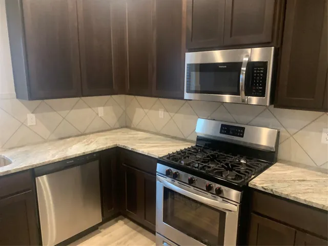 a kitchen with granite countertop stainless steel appliances a stove a microwave and oven