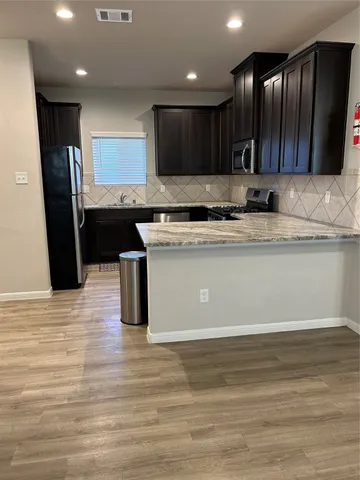 a kitchen with stainless steel appliances granite countertop a sink a stove and a wooden floors