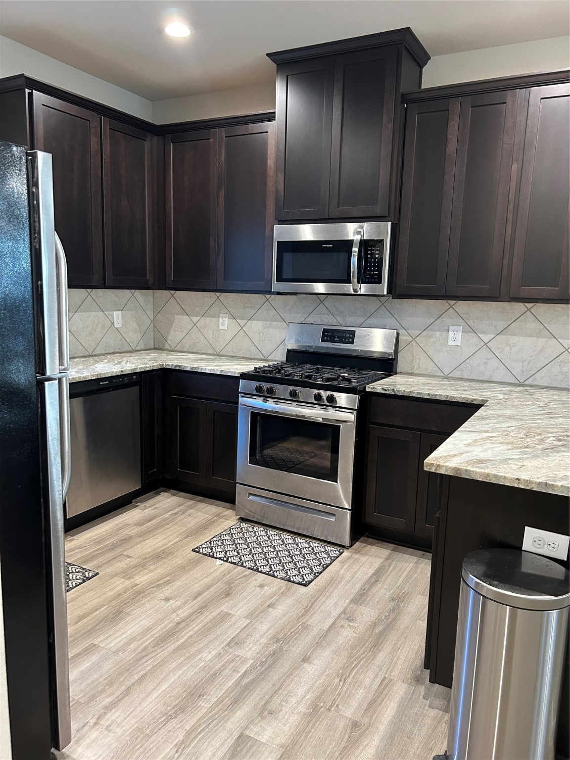 6511 Wenlock Drive Houston, TX 77048 - Photo 6 of 23 a kitchen with stainless steel appliances kitchen island granite countertop wooden cabinets a stove a sink and a counter space