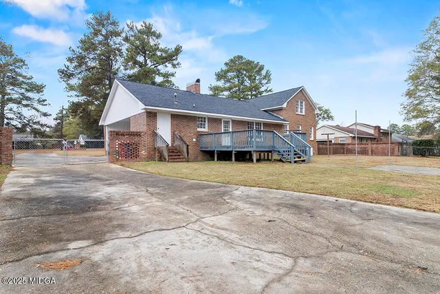 a view of a house with a yard and large trees