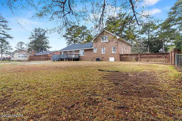 a view of a house with a yard and large tree
