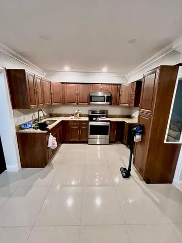 a kitchen with stainless steel appliances a sink a stove a refrigerator cabinets and a window