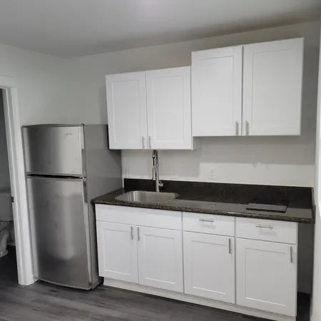 a kitchen with granite countertop white cabinets and refrigerator