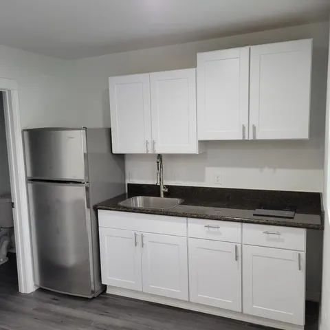 a kitchen with granite countertop white cabinets and refrigerator