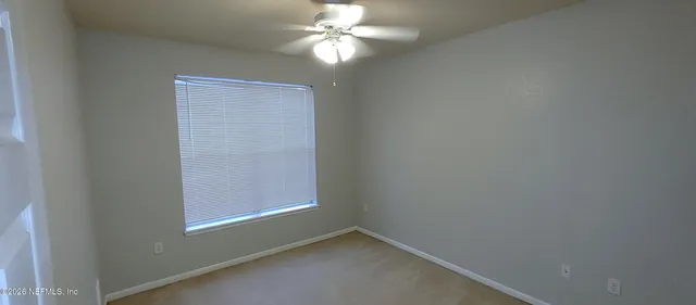an empty room with windows and fan